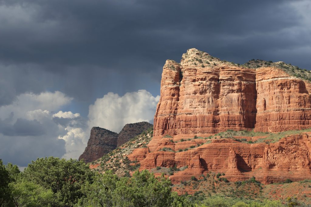 Red sandstone formations under a stormy sky in Sedona, highlighting the contrasting colors of nature and promoting a sense of peace akin to hypnotherapy in San Mateo, CA.