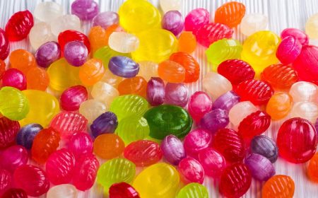 Assorted colorful hard candies scattered on a white wooden surface.